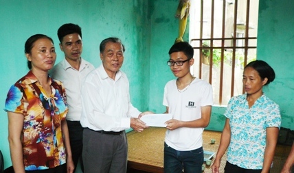 Ông Nguyễn Đình Tích - Phó chủ tịch thường trực Hội khuyến học Hà Nội trao quà cho em Tuân